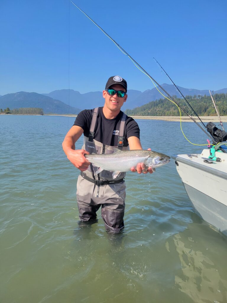 Sturgeon Fishing guide, Ian Biela, holding a salmon in knee high water